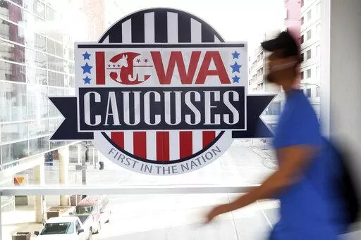 A pedestrian walks past a sign for the Iowa Caucuses on a downtown skywalk, in Des Moines, Iowa, on Feb. 4, 2020. Democrats may be moving toward shaking up their presidential nominating process starting in 2024. They're poised to boot Iowa from the lead-off spot as part of a broader effort to allow to go earlier less overwhelmingly white states that better reflect the party's diverse electorate. (AP Photo/Charlie Neibergall, File)