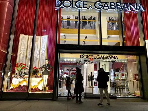 People stand outside the Dolce & Gabbana store on Fifth Avenue, Nov. 21, 2021, in New York. Dolce&Gabbana has become the first Italian fashion house to bring its beauty division in-house, a move that the CEO said Tuesday would strengthen the link between beauty and fashion, and help build inroads with younger consumers.  (AP Photo/Pamela Hassell, file)