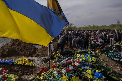 Friends and relatives attend the funeral of Ukrainian serviceman Andrii Vorobiov at the Kryvyi Rih cemetery in eastern Ukraine, Monday, April 24, 2023. (AP Photo/Bernat Armangue)