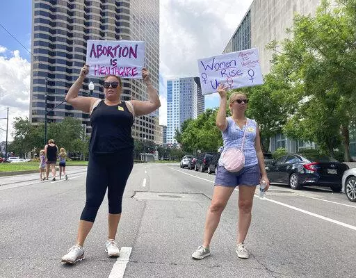 Protesters wave signs and demonstrate in support of abortion access in front of a New Orleans courthouse Friday July 8, 2022. Inside the courthouse a judge was hearing arguments on the state's trigger law designed to outlaw almost all abortions. (AP Photo/Rebecca Santana)