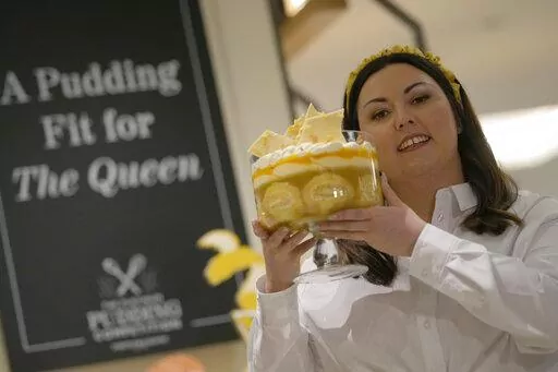 Jemma Melvin the Platinum Jubilee Pudding winner poses for the media with her creation, at a department store in London, Friday, May 13, 2022. Jemma was chosen from over 5000, entries. The 31-year-old copywriter's seven-layer lemon Swiss roll and amaretti trifle beat 5,000 desserts in a U.K.-wide competition to become the official pudding — or dessert, if you’re not British — of the Queen’s Platinum Jubilee. (AP Photo/Alastair Grant)