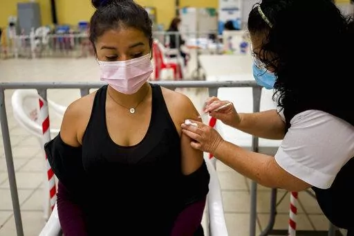 A healthcare worker administers an AstraZeneca booster shot for COVID 19 at a vaccination center in Guatemala City, Tuesday, March 1, 2022.  (AP Photo/Moises Castillo)