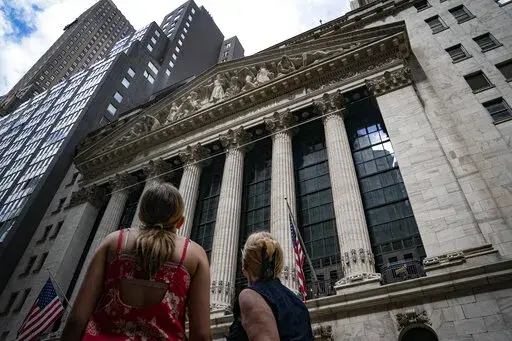Pedestrians pass the New York Stock Exchange on July 14, 2022, in New York. The U.S. economy is caught in an awkward, painful place. A confusing one, too. Growth appears to be sputtering, home sales are tumbling and economists warn of a potential recession ahead. But consumers keep spending, businesses keep posting profits and the economy keeps adding hundreds of thousands of jobs a month. (AP Photo/John Minchillo, File)