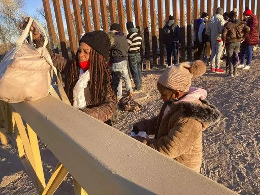 A Cuban woman and her daughter wait in line to be escorted to a Border Patrol van for processing in Yuma, Ariz., Sunday, Feb. 6, 2022, hoping to remain in the United States to seek asylum. For nationalities that don't need a visa, Mexico is often the ticket to seeking asylum in the United States. (AP Photo/Elliot Spagat)