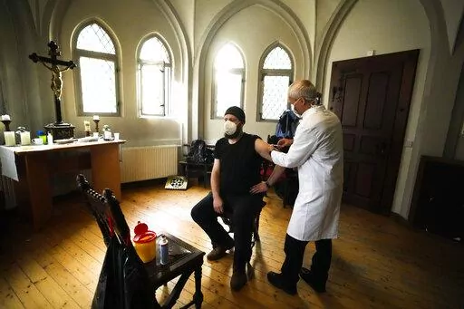 A doctor gives a man a vaccination against coronavirus inside the St. Petri church in Chemnitz, Germany, Sunday, Dec. 12, 2021. Pastor Christoph Herbst at St. Petri church is one of several Lutheran leaders who have been promoting vaccinations in a region that is among the hardest hit by the virus. (AP Photo/Markus Schreiber)